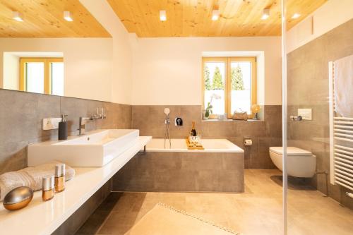 een badkamer met een bad, een wastafel en een toilet bij "Landhaus Panorama" - Luxuriöse Ferienwohnungen in bester Lage für gehobene Ansprüche in Oberstdorf