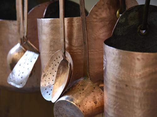 a group of copper utensils hanging from a wall at Europa Mountain Apartments in Alleghe