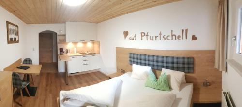 a bedroom with a white bed and a kitchen at Pfurtschell in Neustift im Stubaital