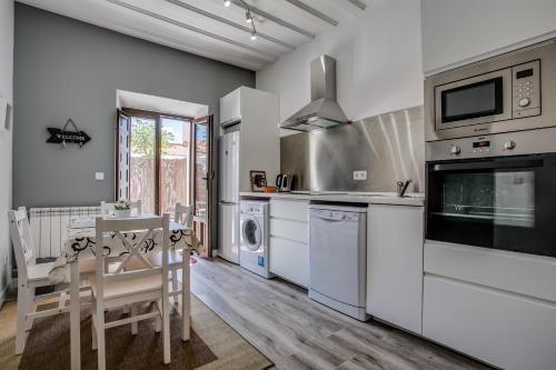 una cocina con electrodomésticos blancos, mesa y sillas en Casa La Cuadra, en Brunete