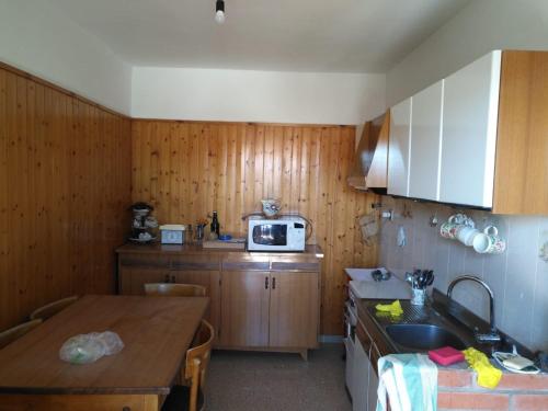 eine Küche mit Holzschränken, einem Tisch und einer Mikrowelle in der Unterkunft Casetta indipendente al lago di Bolsena in Valentano