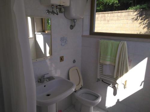 ein Bad mit einem Waschbecken, einem WC und einem Fenster in der Unterkunft Casetta indipendente al lago di Bolsena in Valentano