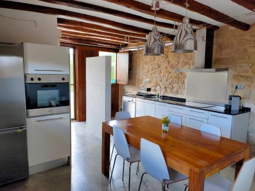 a kitchen with a wooden table and white appliances at La Era De Pepe in Calaceite