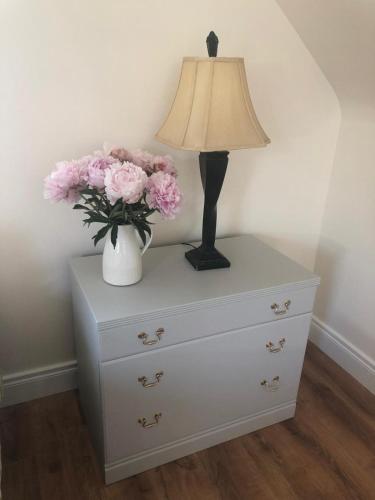 a white dresser with a lamp and flowers on it at Drum Manor Apartment Hillsborough BT26 6PU in Hillsborough