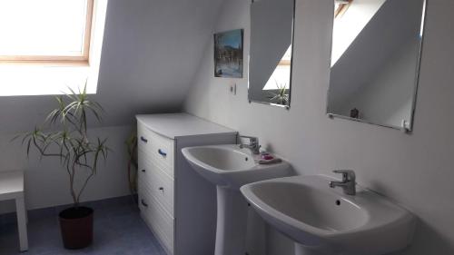 uma casa de banho branca com 2 lavatórios e 2 espelhos em Le Grand Orient em Annoville