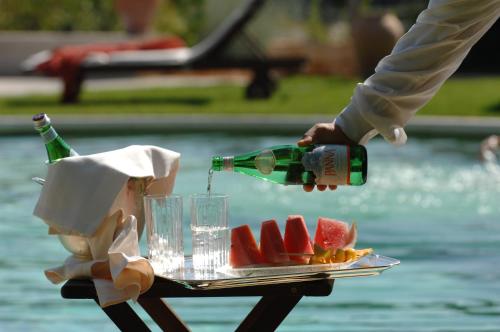 a person is holding a bottle of wine and a plate of watermelon at Relais Villa San Martino in Martina Franca