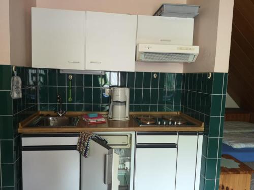 a small kitchen with white cabinets and green tiles at Haus Franziska in Leck