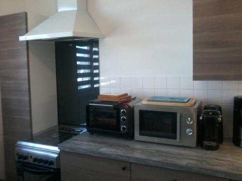 un micro-ondes posé sur un comptoir dans une cuisine dans l'établissement Chemin des Forrières, à Saint-Aubin-sur-Mer