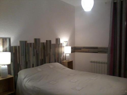 1 dormitorio con 1 cama blanca y 2 lámparas en Chemin des Forrières en Saint-Aubin-sur-Mer