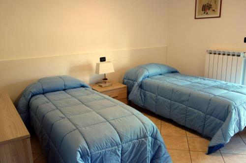 two beds in a bedroom with blue comforter at Appartamento Lidarno in Lidarno