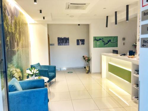 a lobby with two blue chairs and a counter at 16 Lakes Hotel in Grabovac