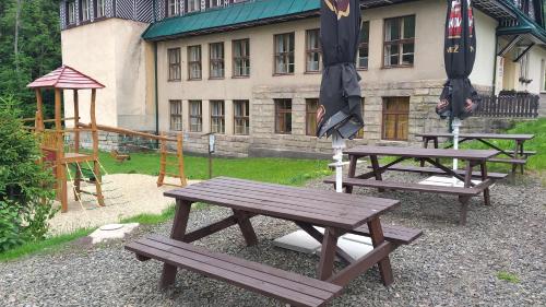 two picnic tables with umbrellas in front of a building at Chalupa 335 in Vítkovice