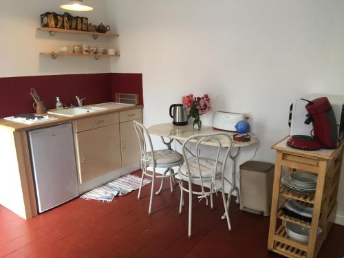uma cozinha com uma mesa e cadeiras e um lavatório em La Bernache em Saint-Satur