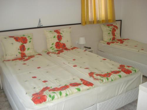 Dos camas en un dormitorio con flores rojas. en Kupenova Guest House, en Sozopol