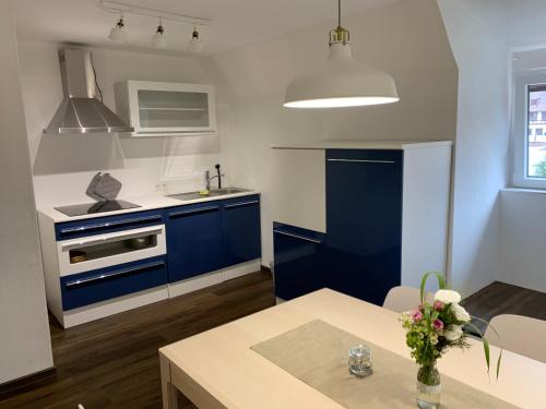 a kitchen with blue cabinets and a table at Pension Deckenpfronn in Deckenpfronn
