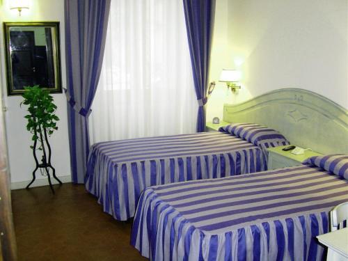 two beds in a hotel room with purple and white stripes at Casa Gori in Certaldo