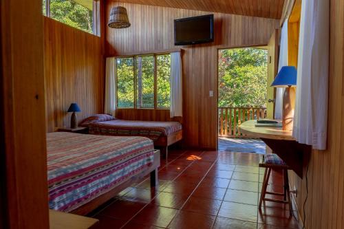 a bedroom with two beds and a balcony with windows at Arco Iris Lodge in Monteverde Costa Rica