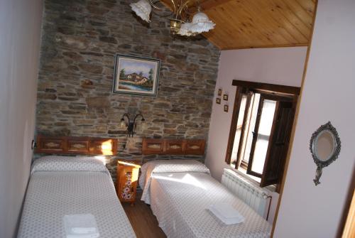 a room with two beds and a stone wall at Casa Bell in Manzanedo de Valdueza