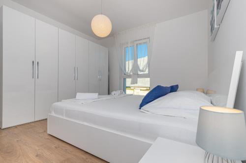a white bedroom with a large white bed and a window at Apartment Vivien in Crikvenica