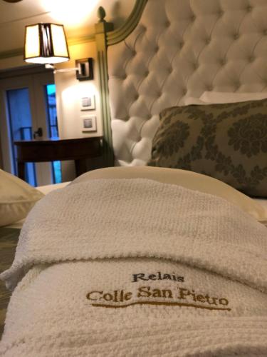 a bed with a white blanket on top of it at Relais Colle San Pietro in Verona