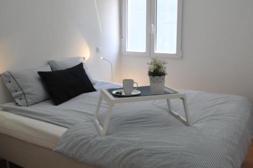 a white bed with a table with a cup on it at VISTA PLAYA Y MAR - sea view, wifi and AC in Melenara