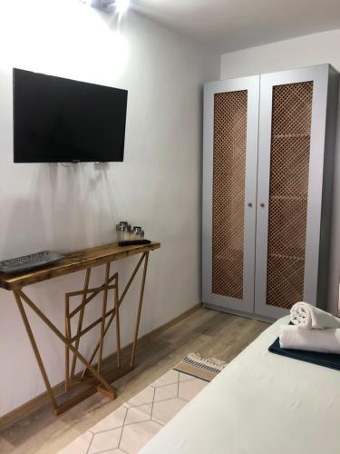 a bedroom with a desk with a television on the wall at Casa Mediterana in 2 Mai