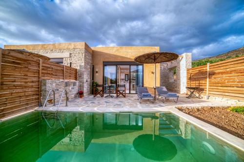een zwembad met 2 stoelen en een parasol naast een huis bij Olive Luxury Suites - ADULTS ONLY in Kamilari