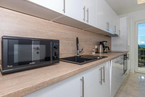 a kitchen with a microwave and a counter with a sink at Apartment Vivien in Crikvenica