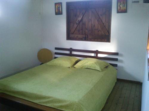 - une chambre avec un lit vert et une tête de lit en bois dans l'établissement Bungalow Chez Madly, à Saint-François