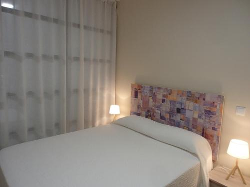 een slaapkamer met een wit bed en 2 lampen bij Apartamento El Aljibe de la Luz in Toledo
