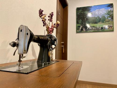 a sewing machine on a table with a vase of flowers at Hotel La Cuna del Sella in Oseja de Sajambre
