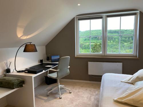 a bedroom with a desk and a bed and a window at L'Auf der Tomm in Martelange