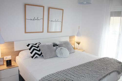 a white bedroom with a large white bed with pillows at Apartamentos La Herradura Terraza in Haro