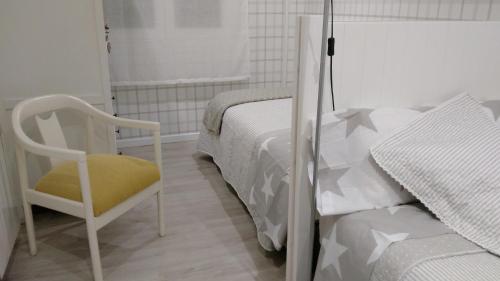 Apartamento Madrid Retiro M-30 في مدريد: غرفة نوم بيضاء بسرير وكرسي