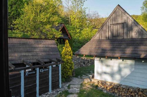 an old barn and a building next to a stone wall at Zbojnícke Chalúpky in Čavoj