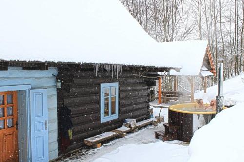a log cabin with snow on the roof at Zbojnícke Chalúpky in Čavoj