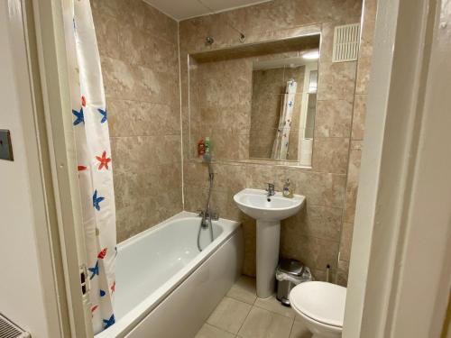 a bathroom with a sink and a tub and a toilet at Grand Heights Suites in London