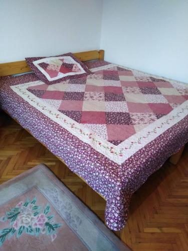 a bed with a quilt on top of it at Apartman Tara in Vrdnik