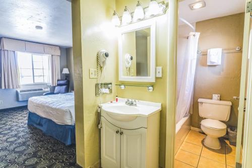 a bathroom with a sink and a toilet and a bed at Montrose Valley Lodge in Montrose