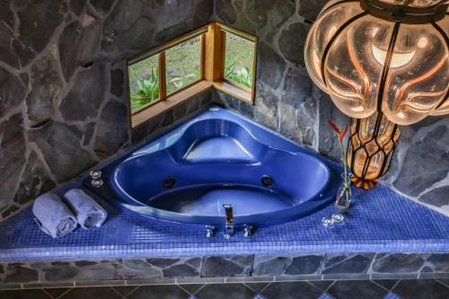 a blue tub in a stone bathroom with a chandelier at Arco Iris Lodge in Monteverde Costa Rica