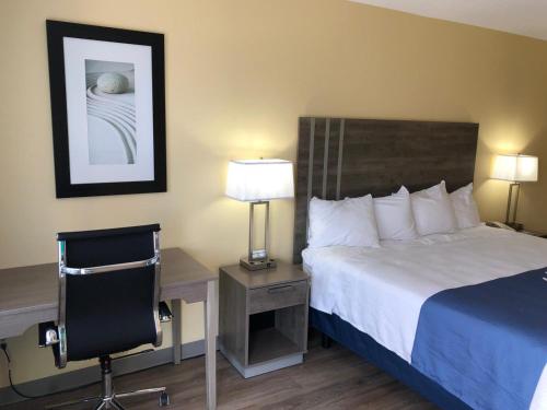 a hotel room with a bed and a desk and a chair at Days Inn by Wyndham Cape Carteret in Cape Carteret