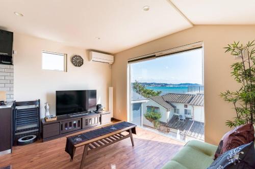 a living room with a tv and a large window at Villa Kamakura in Kamakura