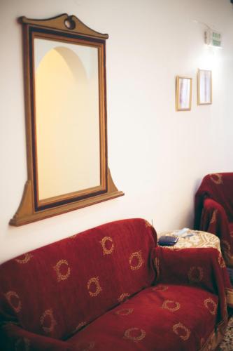 a mirror sitting on the wall above a red couch at Pension Mylos in Agios Nikolaos