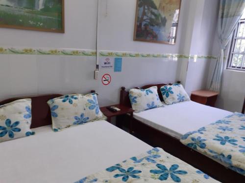 a room with two beds with blue and white pillows at Thanh Binh Hotel in Buon Ma Thuot
