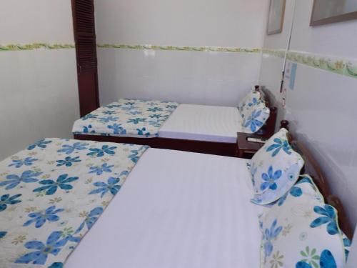 2 letti in una camera con lenzuola bianche e blu di Thanh Binh Hotel a Buôn Ma Thuột