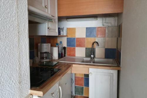 une petite cuisine avec un évier et une cuisinière dans l'établissement studio cabines 6 couchages 150 m de la plage et à quelques secondes des commerces wifi gratuit, à La Grande Motte