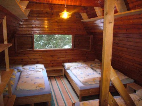 two beds in a log cabin with a window at Chata pri potoku in Zuberec
