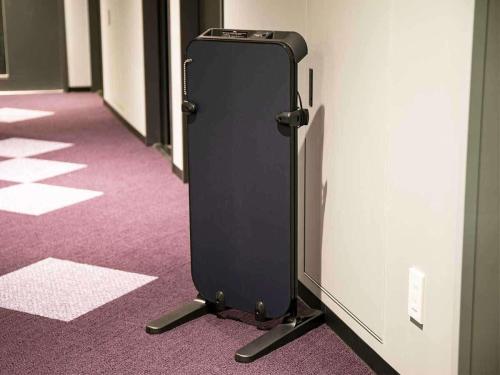 a black refrigerator on the floor of a hallway at KOKO HOTEL Hidatakayama - formaly Hotel Wing Hida Takayama in Takayama