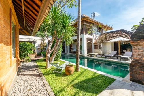a backyard with a swimming pool and a house at Villa Angsa by Nakula in Sanur