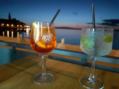 two wine glasses sitting on a table with a view of the water at Apartments Villa Anton in Poreč